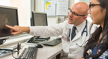 Dr. Daniel Catenacci looking at a scan on a computer with a nurse