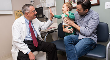 Dr. Baroody high fiving a pediatric patient with his dad