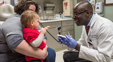 Dr. Russell Reid with examining pediatric patient