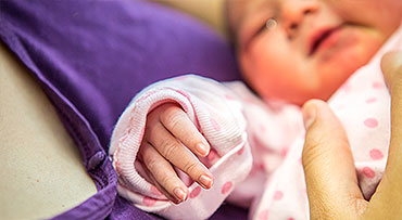 Close-up of newborn girl held by mom