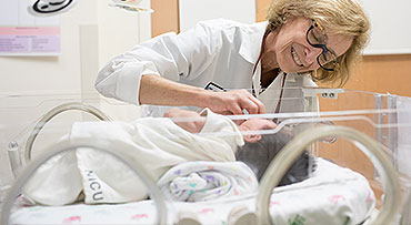Pediatric surgeon Jessica Kandel, MD, checking on a baby in the NICU