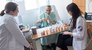 Pharmacists reviewing medications with patient post surgery