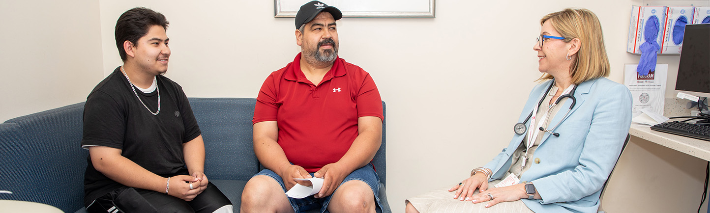 Image of Dr. Tara Henderson working with pediatric cancer patient and his parent
