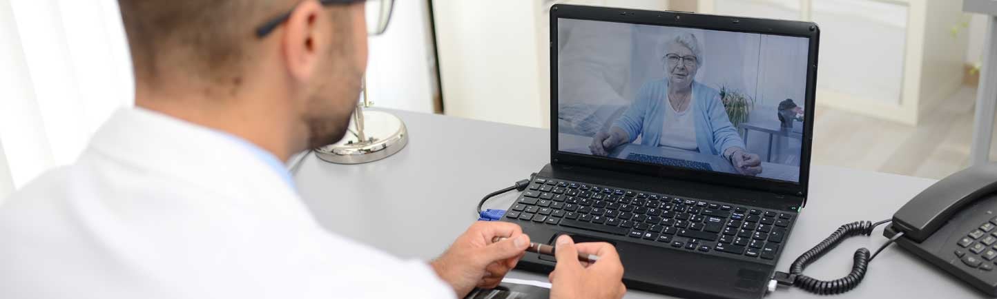 Physician looking at laptop of female patient, doing telemedicine visit