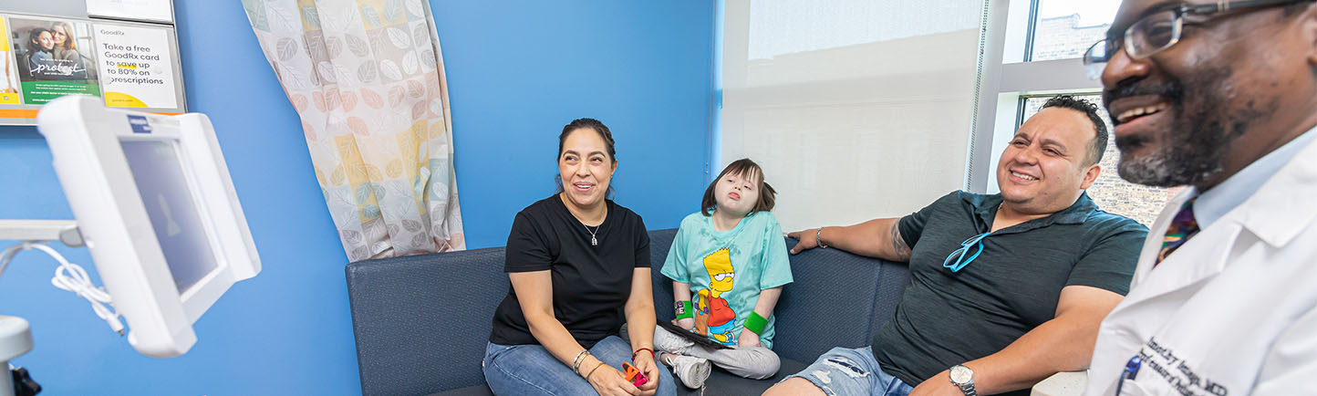 Image of Dr. Sentongo working with a pediatric patient and parents