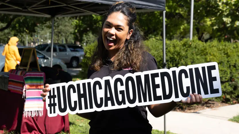 Woman outside holding a #UChicagoMedicine sign