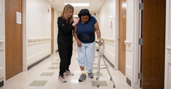 Female patient walking with her female physical therapist