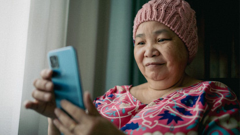 older Asian woman with pink hat, holding cell phone