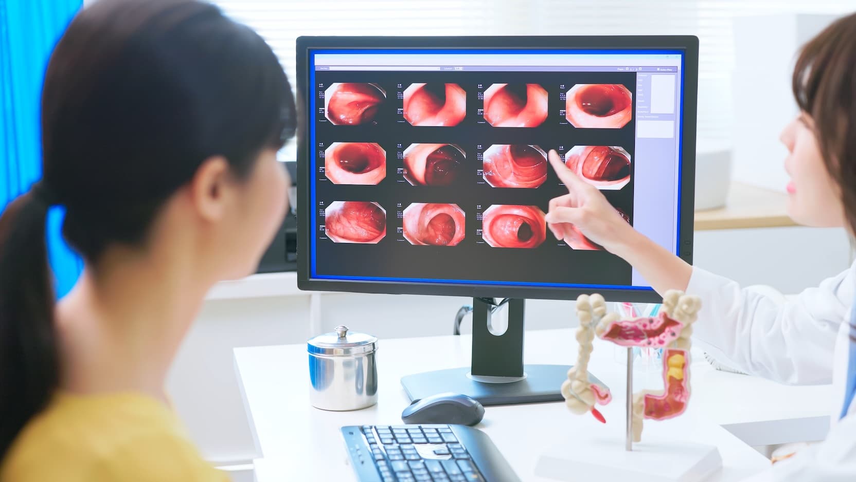 gastroenterology doctor shows screening images to patient on computer screen