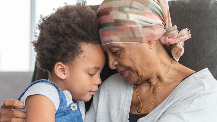 Elderly woman with headscarf hugs grandchild