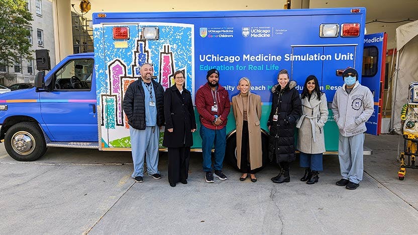 Simulation Center staff pose in front of blue Simulation Mobile Unit