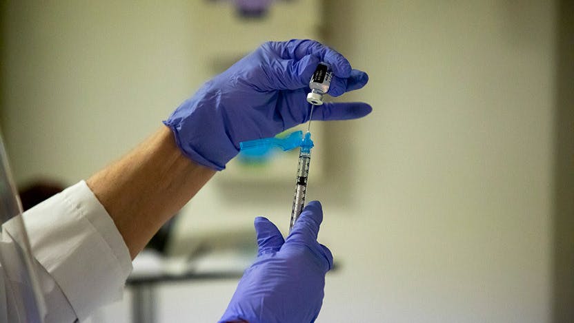 A person filling a syringe with COVID-19 vaccine.