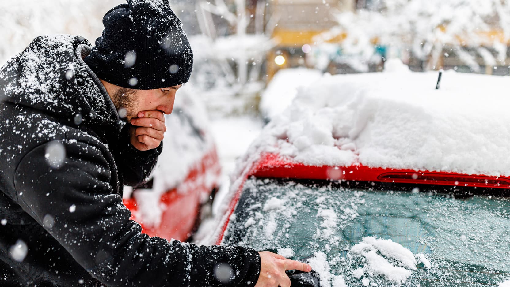 man cleaning his car of snow