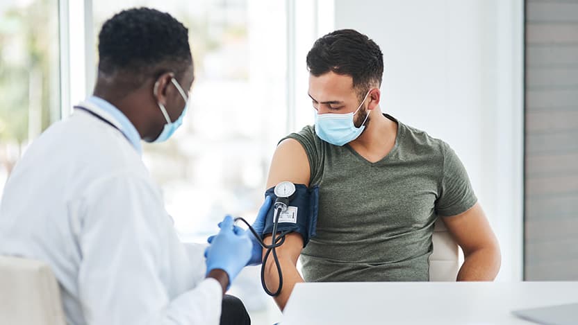 Shot of a doctor examining a young man with a blood pressure gauge