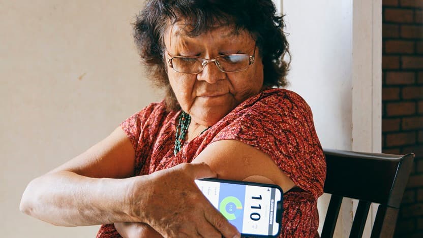 an older navajo woman checks her blood glucose with a smartphone app