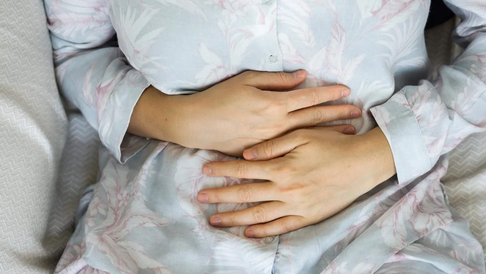close up view of person holding their stomach in pain