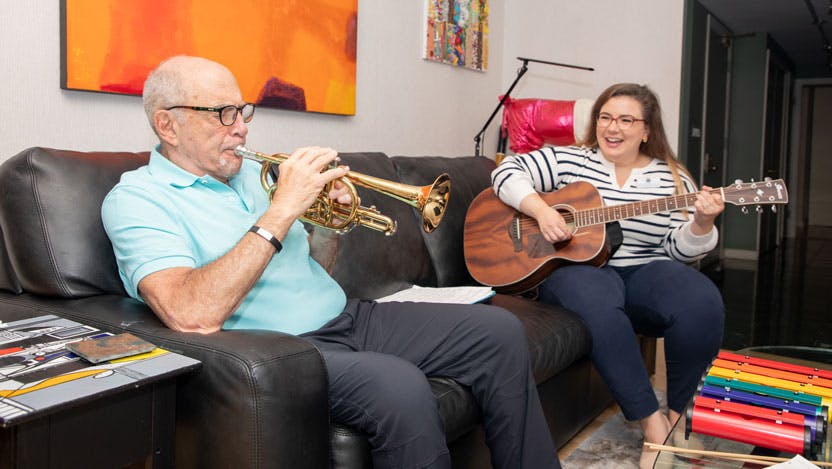 Ted Oppenheimer and female music therapist playing instruments on the couch