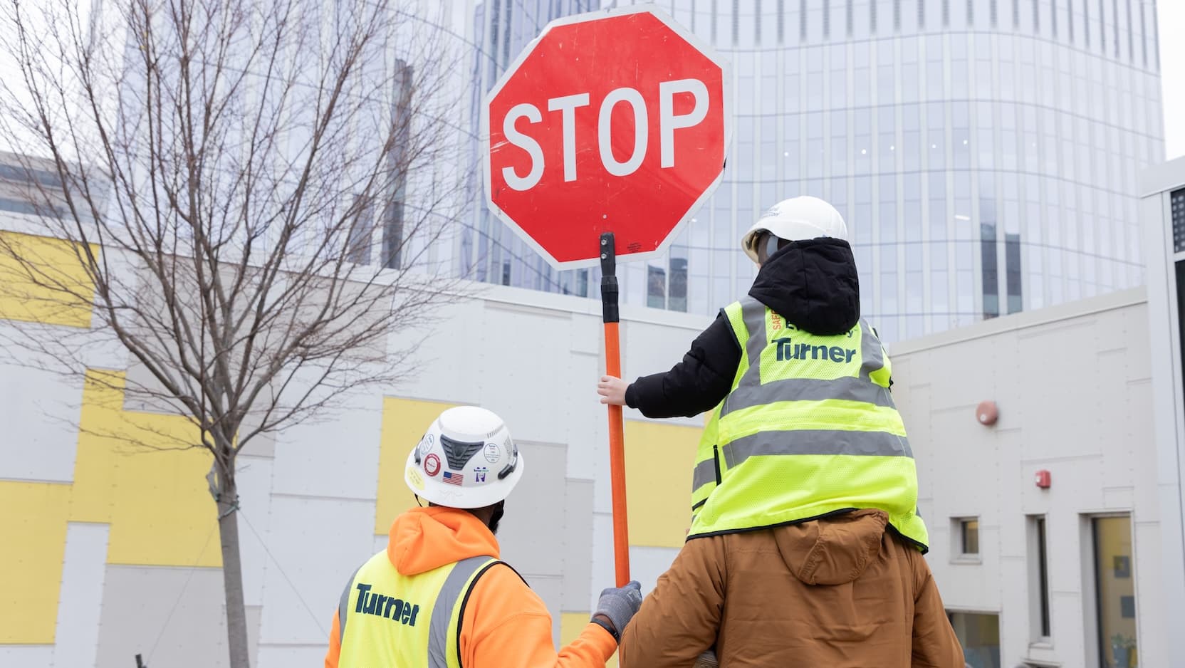 Construction worker and child with stop sign at cancer pavillion