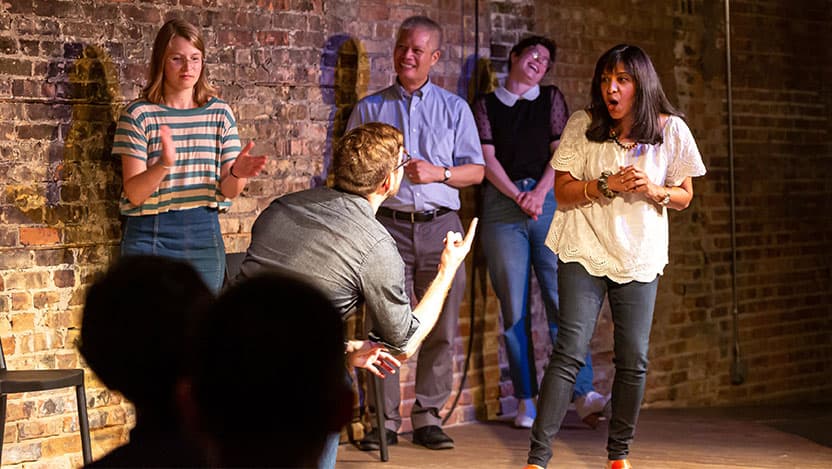Vineet Arora, MD, performs with the improv troupe as Marshall Chin, MD, MPH, and members of the troupe look on