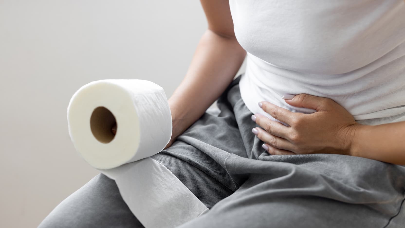 woman feeling stomach holding toilet paper