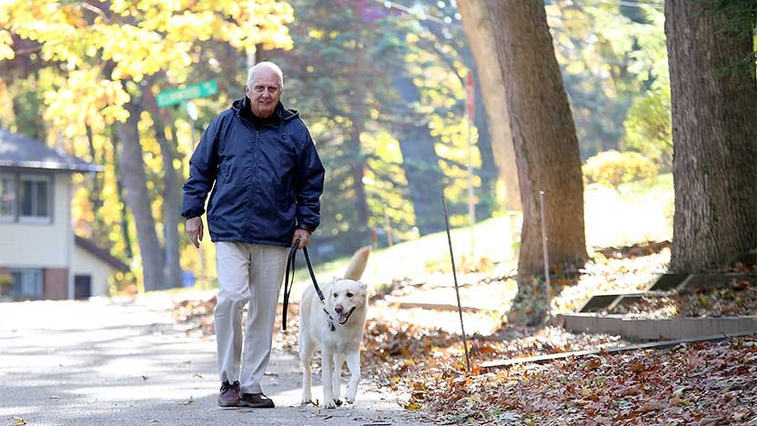 Carl Adams and his dog go on a walk after knee surgery