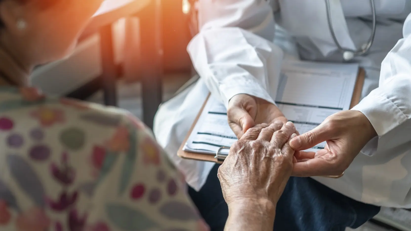 physician holding hand of older patient