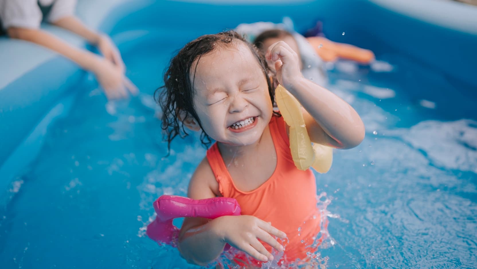 child smiling and swimming touching side of their head