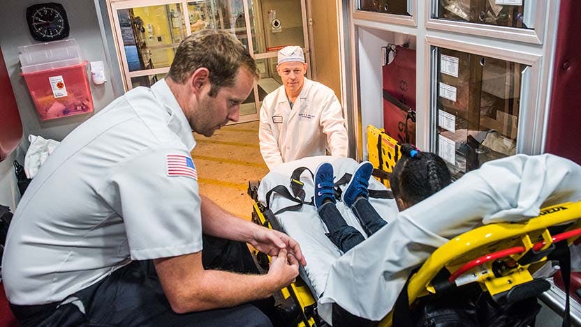 Dr. Mark Slidell helping a patient out of an ambulance