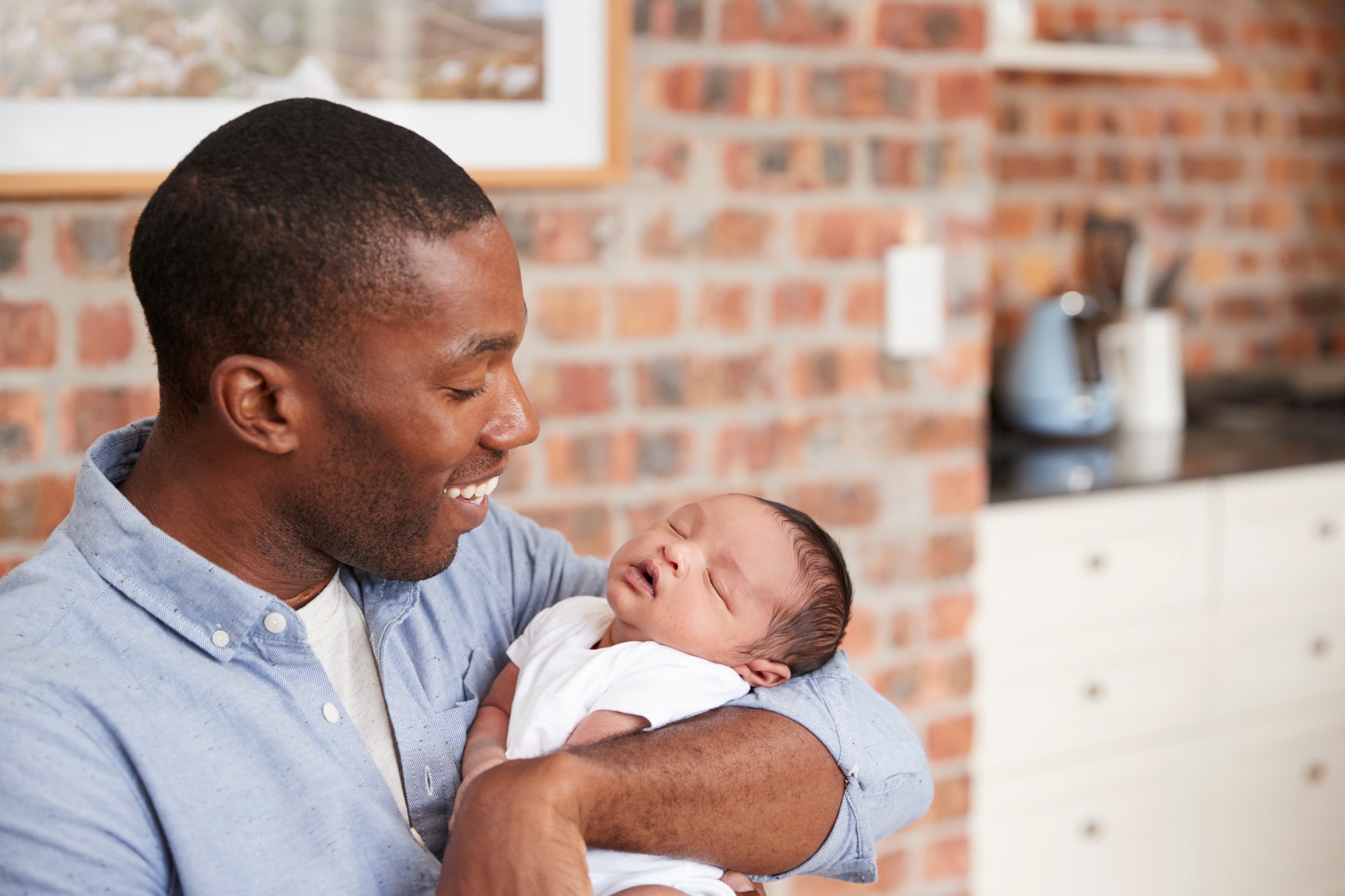 Smiling father holds sleeping newborn
