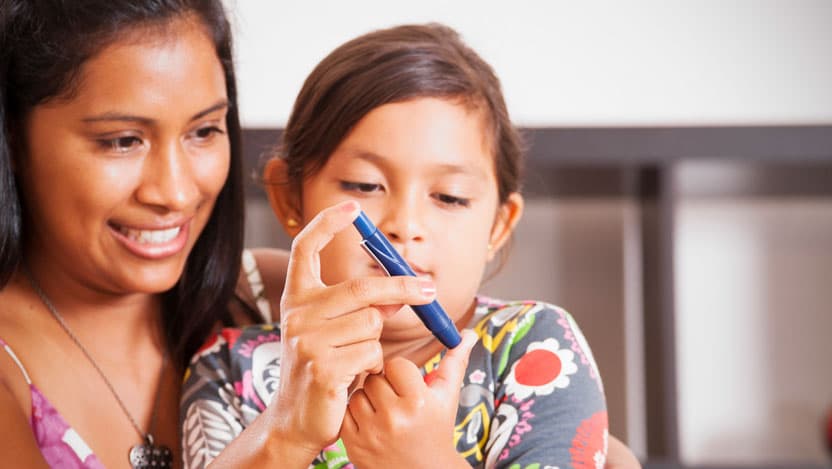 A photograph of a mother helping her diabetic child monitor her blood sugar. 