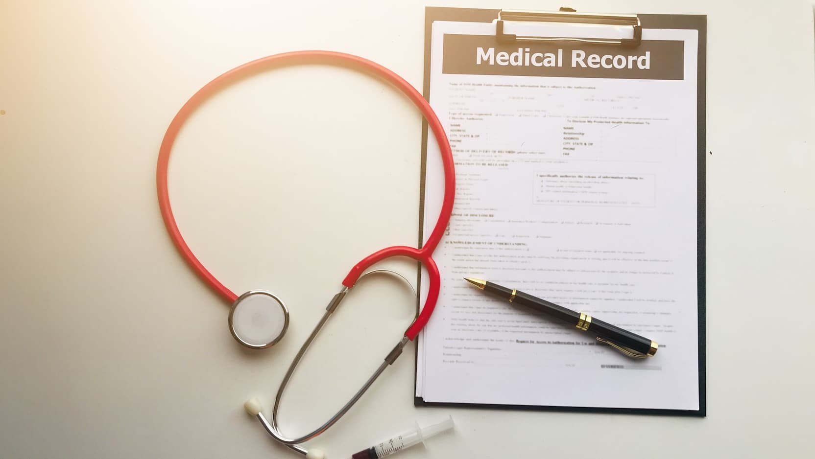 Stock image of a medical record with pen, stethoscope and syringe