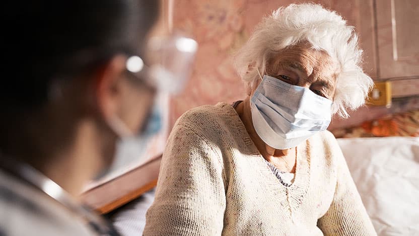 Female doctor doing medical exam of a senior woman at her home.