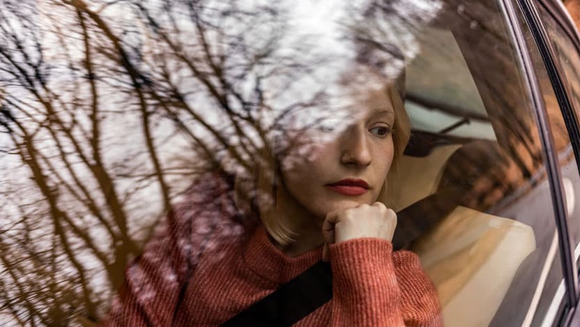 Woman staring out of car window in deep thought