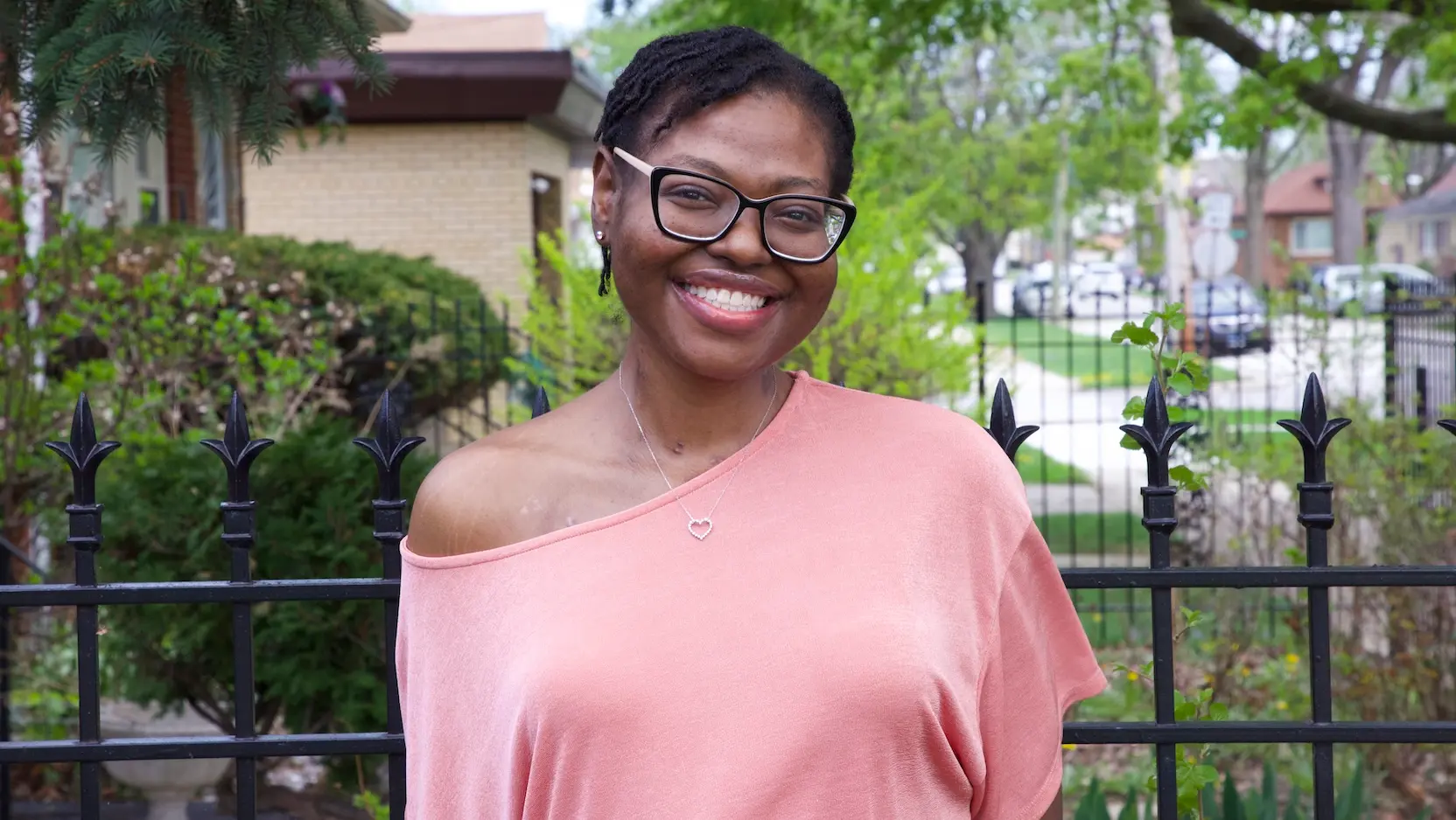 Jasmine Jones in pink shirt in front of black fence