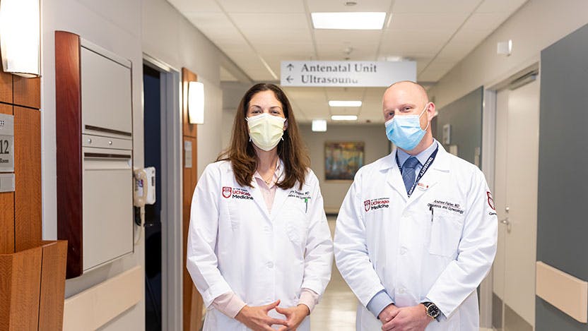 Transabdominal cerclage experts Dr. Laura Douglass and Dr. Andrew Fisher stand masked at UChicago Medicine