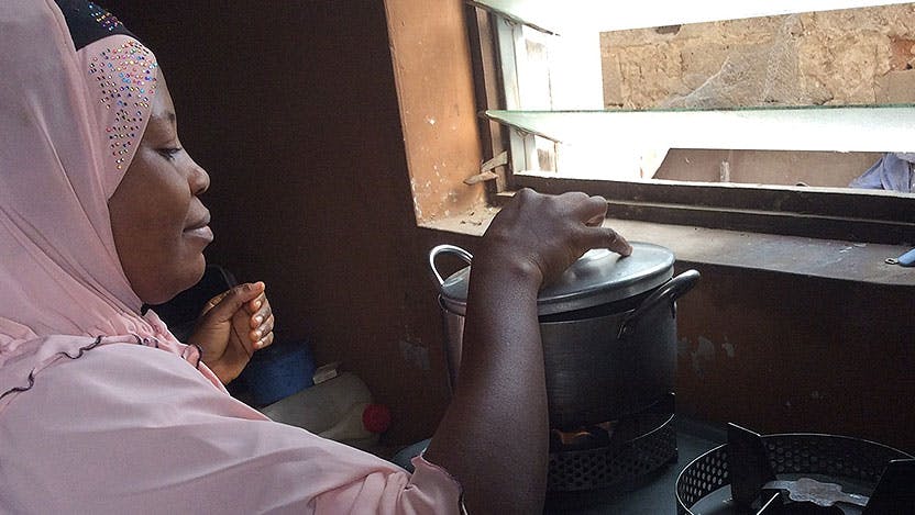 A nigerian woman cooking at a stove