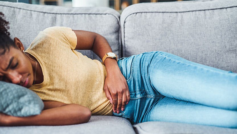 Woman laying on couch in pain with fibroid cramps