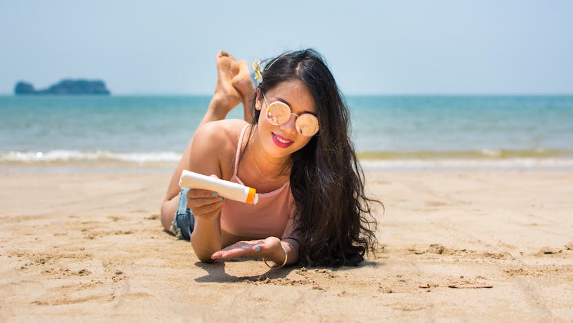 Woman on the beach applying sunscreen
