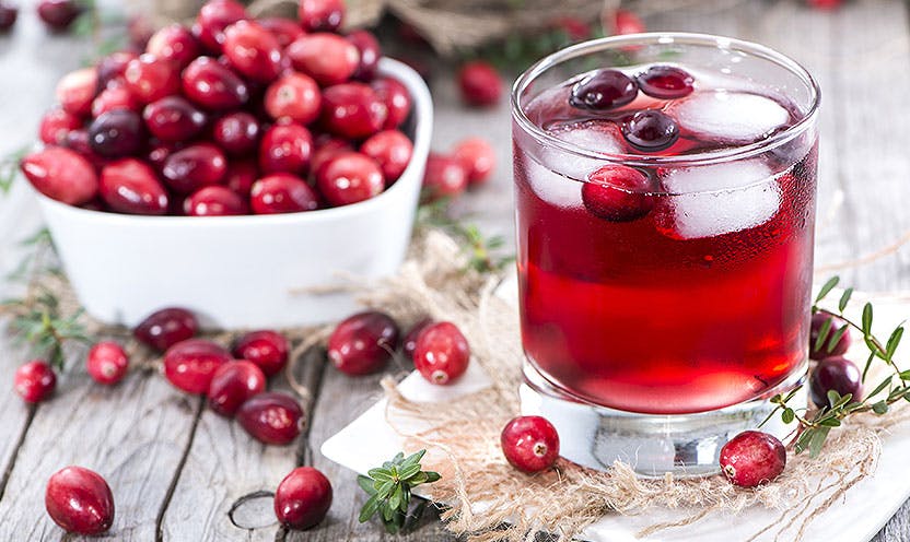 A bowl of cranberries and a glass of cranberry juice