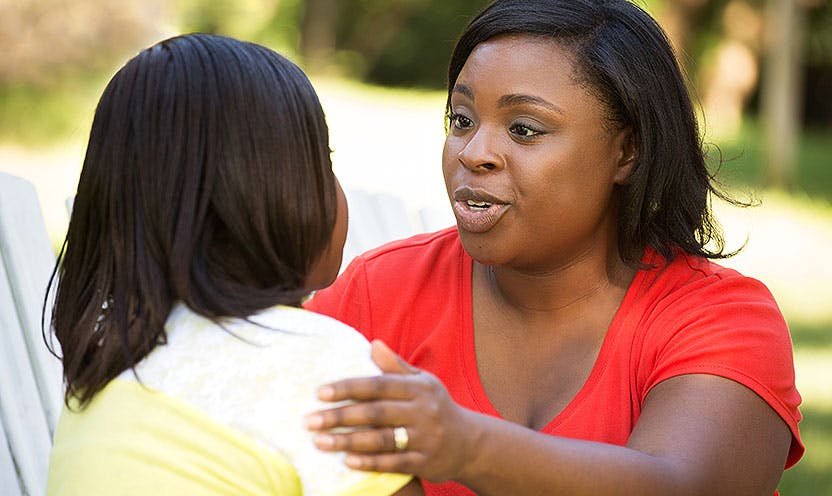 Mom speaks encouragingly to young daughter with hand on shoulder