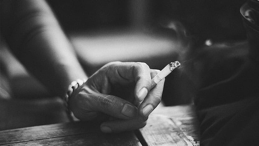Black and white photo of a woman's hand holding a cigarette