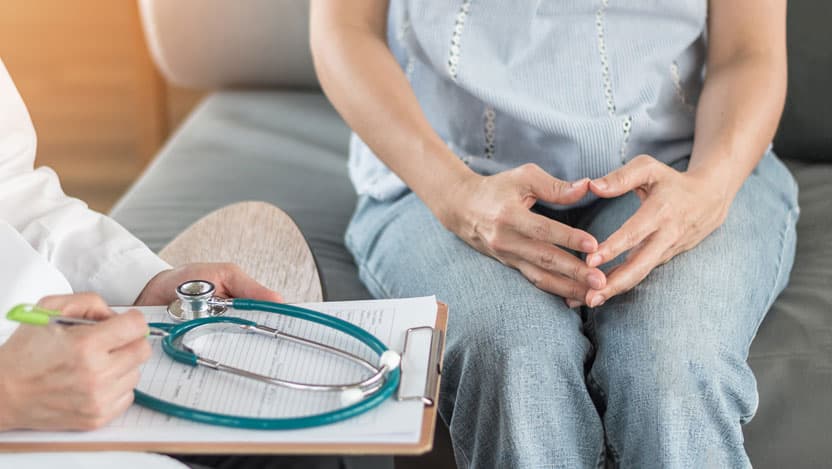 Doctor with clipboard and woman with hands on lap