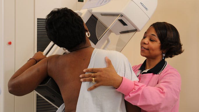 Mammography technician with patient, performing mammography