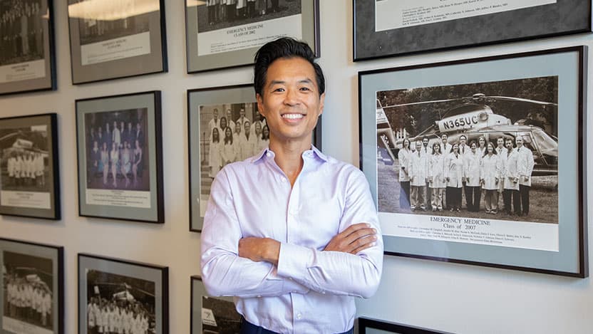 James Ahn posing in front of a the wall of EM class photos