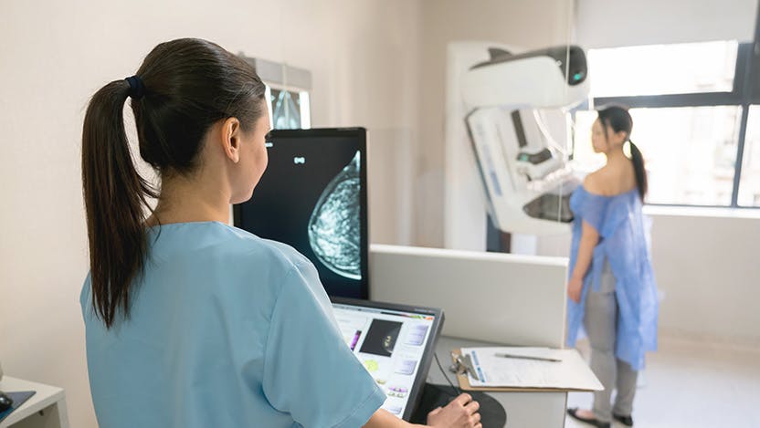 Nurse giving mammogram exam to standing patient
