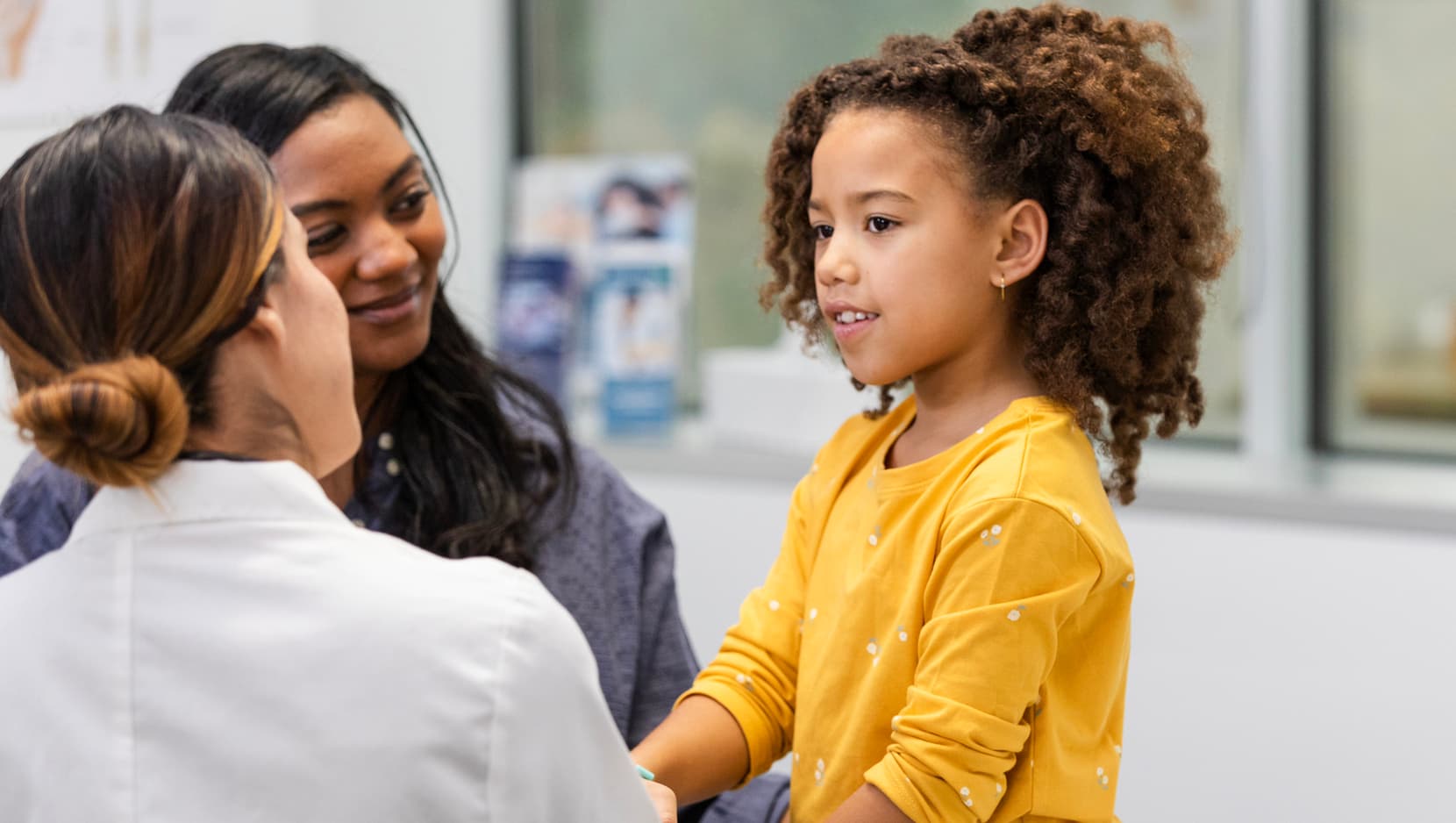 pediatrician-talking-with-young-girl-and-mother-during-checkup