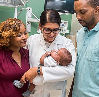 Maternal-fetal medicine specialist Dr. Sarosh Rana holding a newborn with his parents at her side