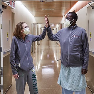 Triple-organ transplant patients, Sarah and Daru, high five each other