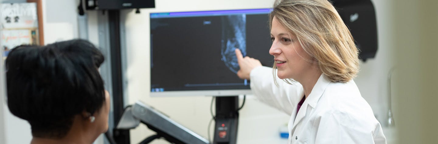 Olwen Hahn, MD, in clinic, pointing to CT scan