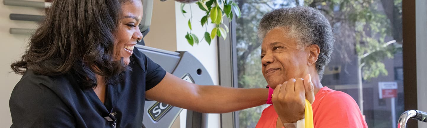 A female patient in a wheel chair receiving physical therapy from a female therapist.